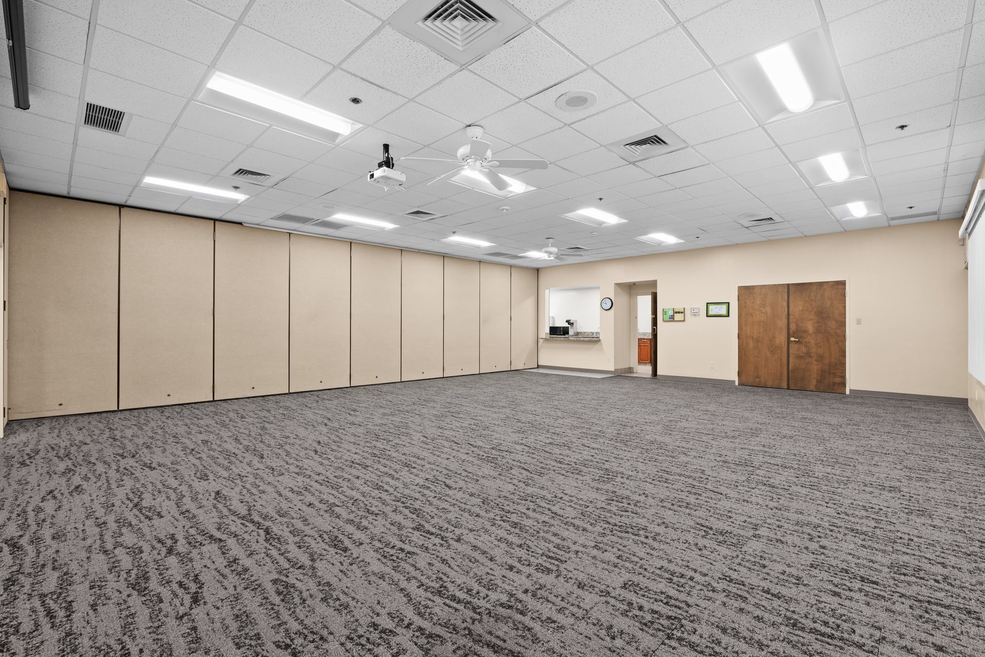 Compact, cozy event room with neutral decor and kitchen access, suitable for club meetings or small gatherings.