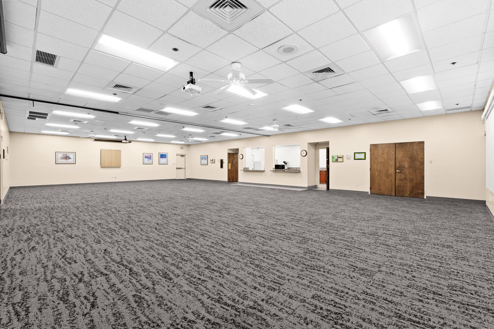 Bright dual-room setup with neutral carpet and folding wall divider, ideal for community meetings or mid-size events.