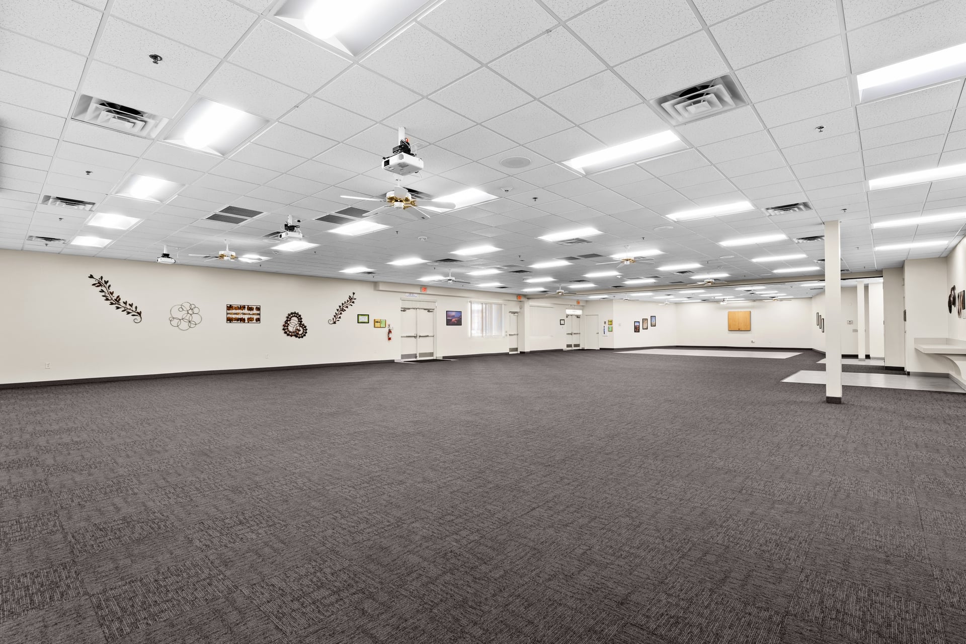 Spacious multi-purpose room with full carpet, ceiling fans, and flexible layout for large gatherings or events at Sun City West Foundation.