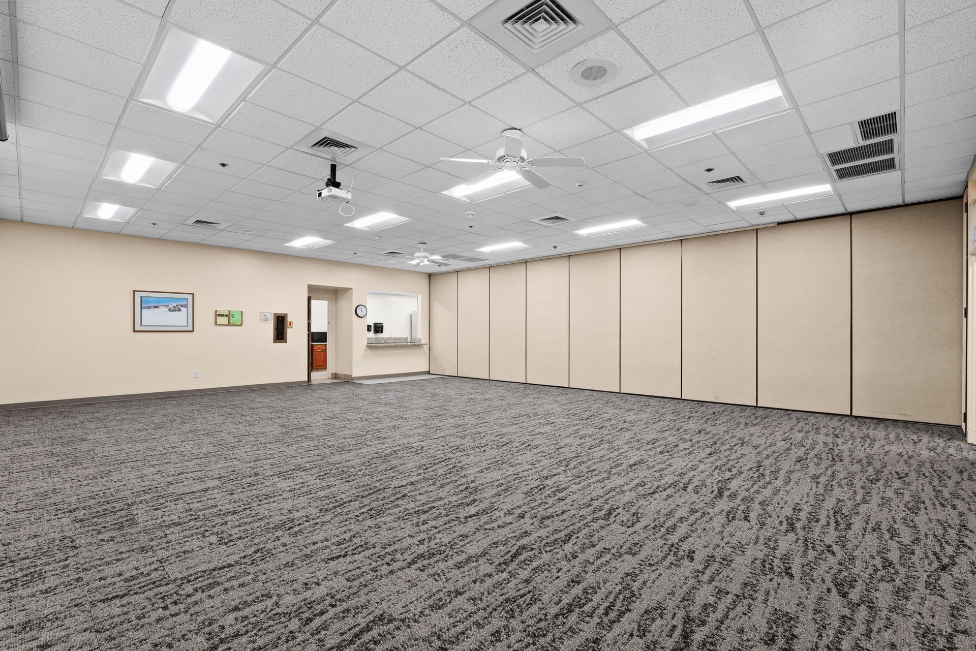 Mid-size meeting room with carpeted floors, framed wall art, and overhead lighting at Sun City West Foundation.