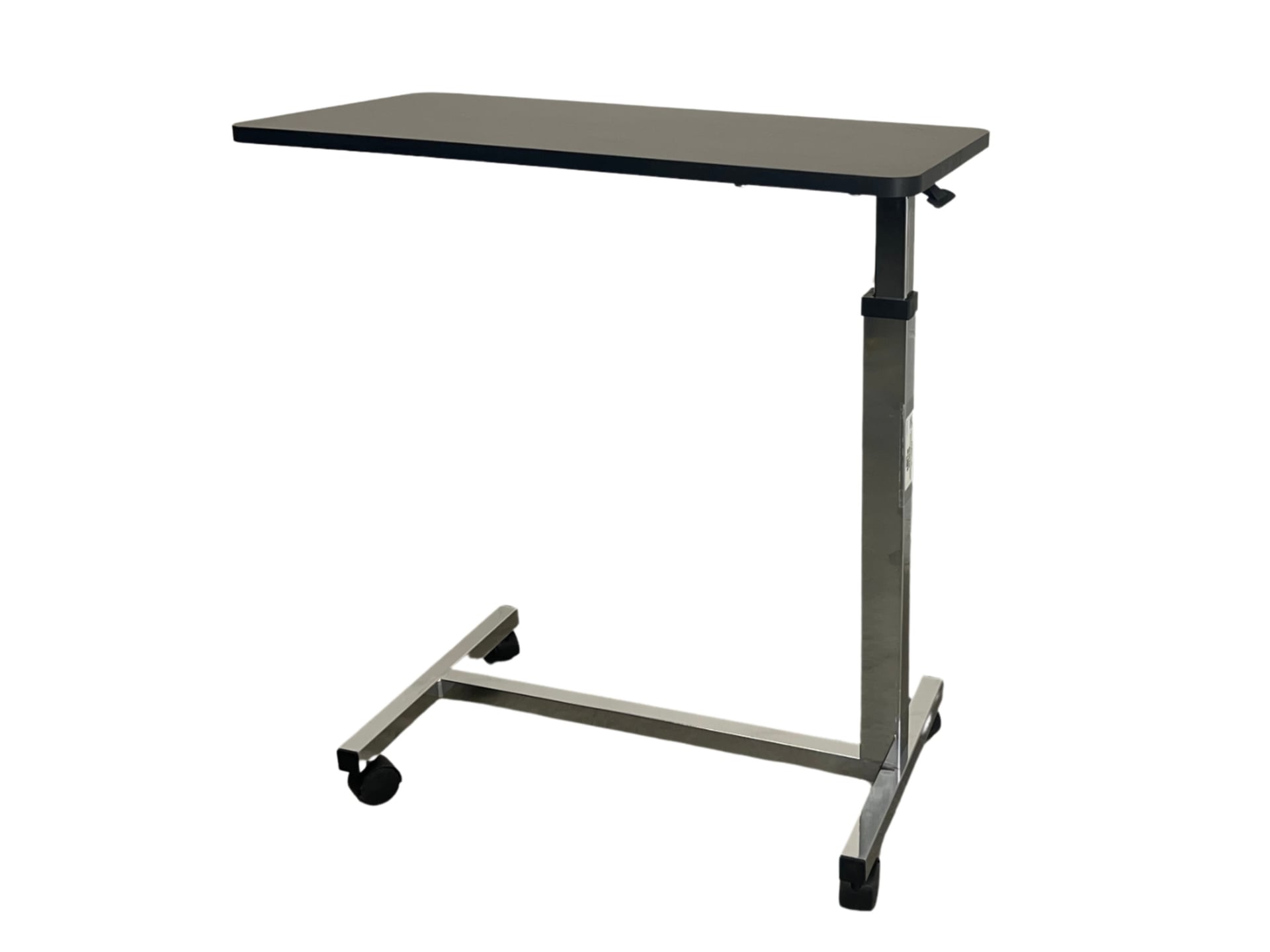 A mobile overbed table featuring a black rectangular top mounted on a single silver telescoping column, supported by a T-shaped base with four small caster wheels for easy positioning.