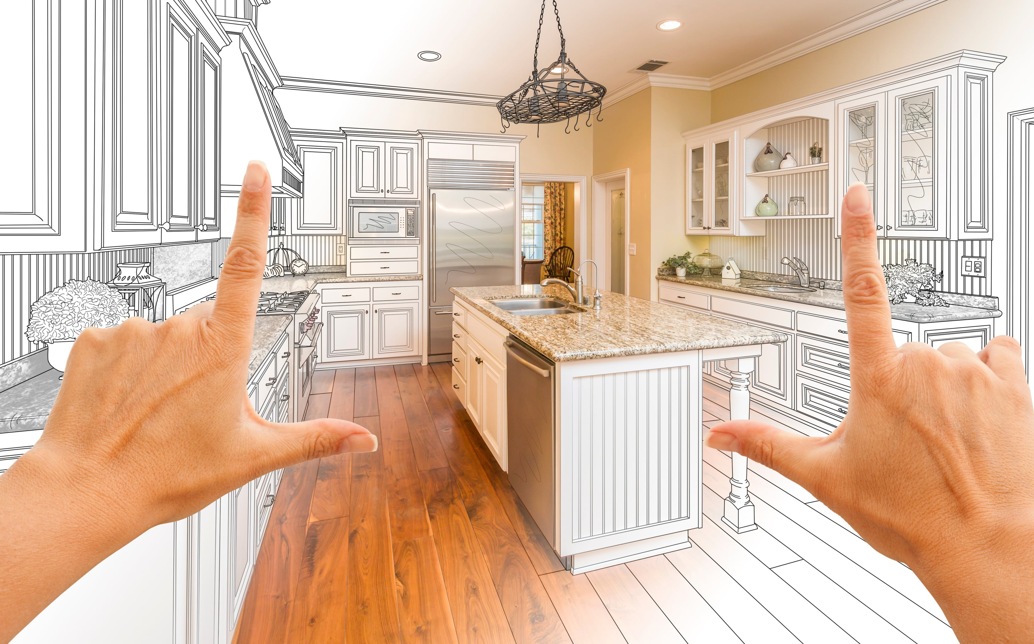 Hands framing a kitchen renovation concept with half of the image showing a finished kitchen and the other half showing design sketches.