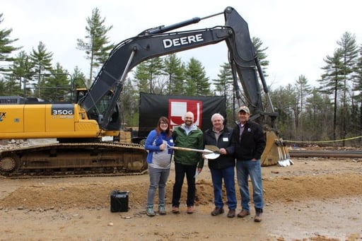 Jewett Construction team and partners celebrate the Center for Wildlife groundbreaking with shovels in front of a large excavator.